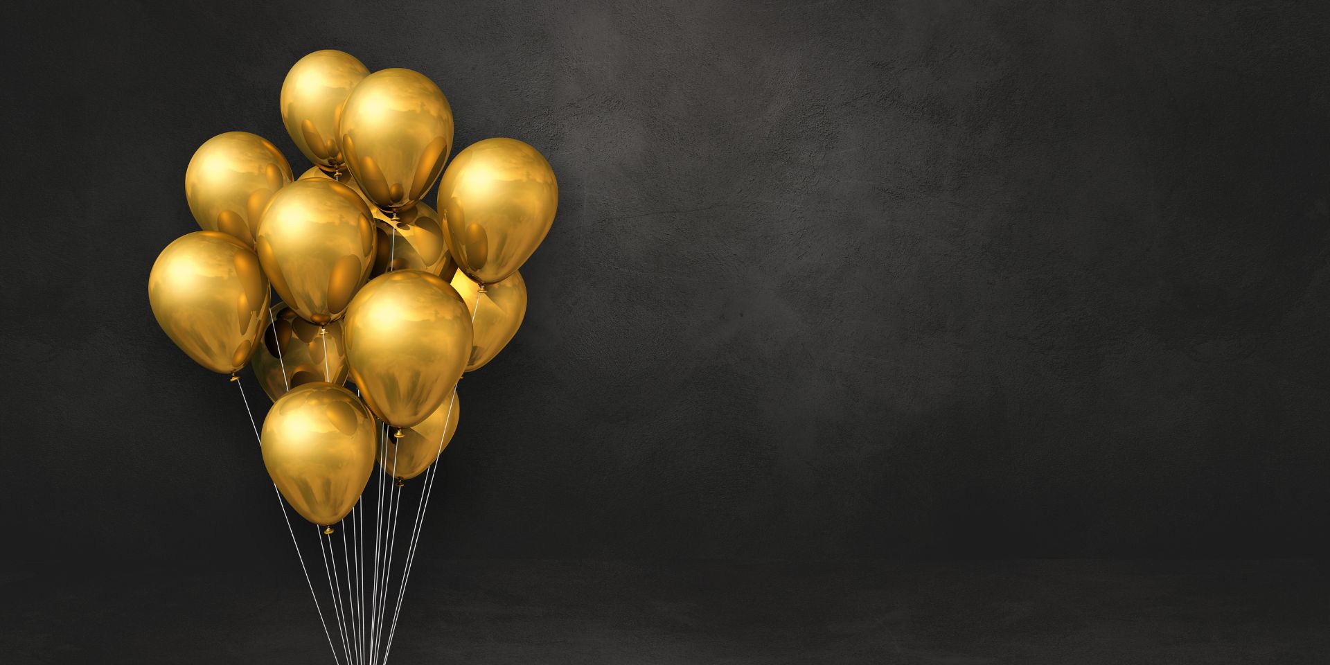 Gold balloons in front of a black wall.