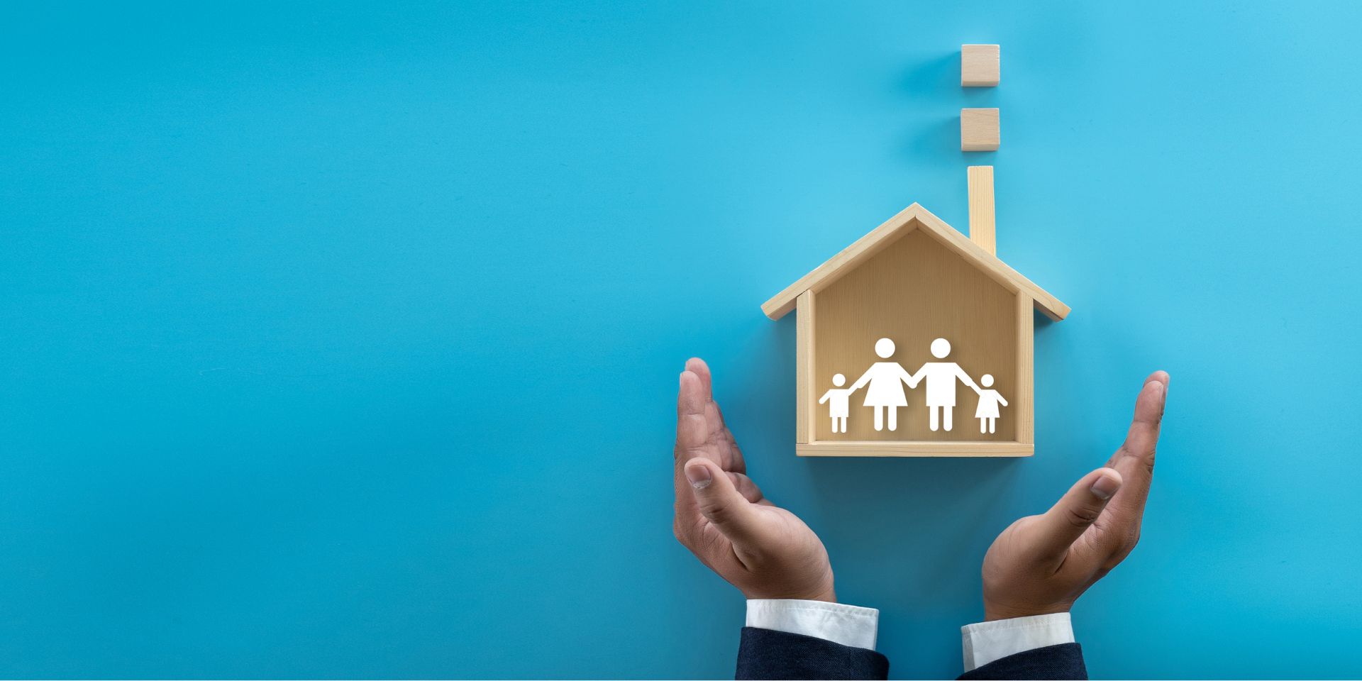 A man's hands holding up a model of a house.