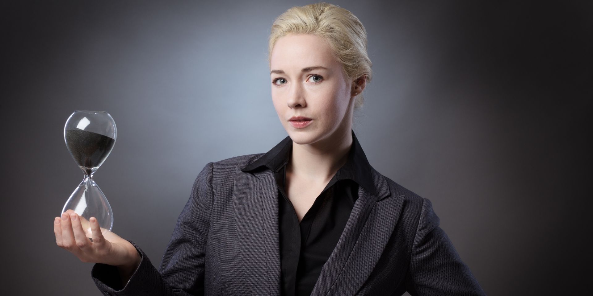 Business woman holds a black sand timer.