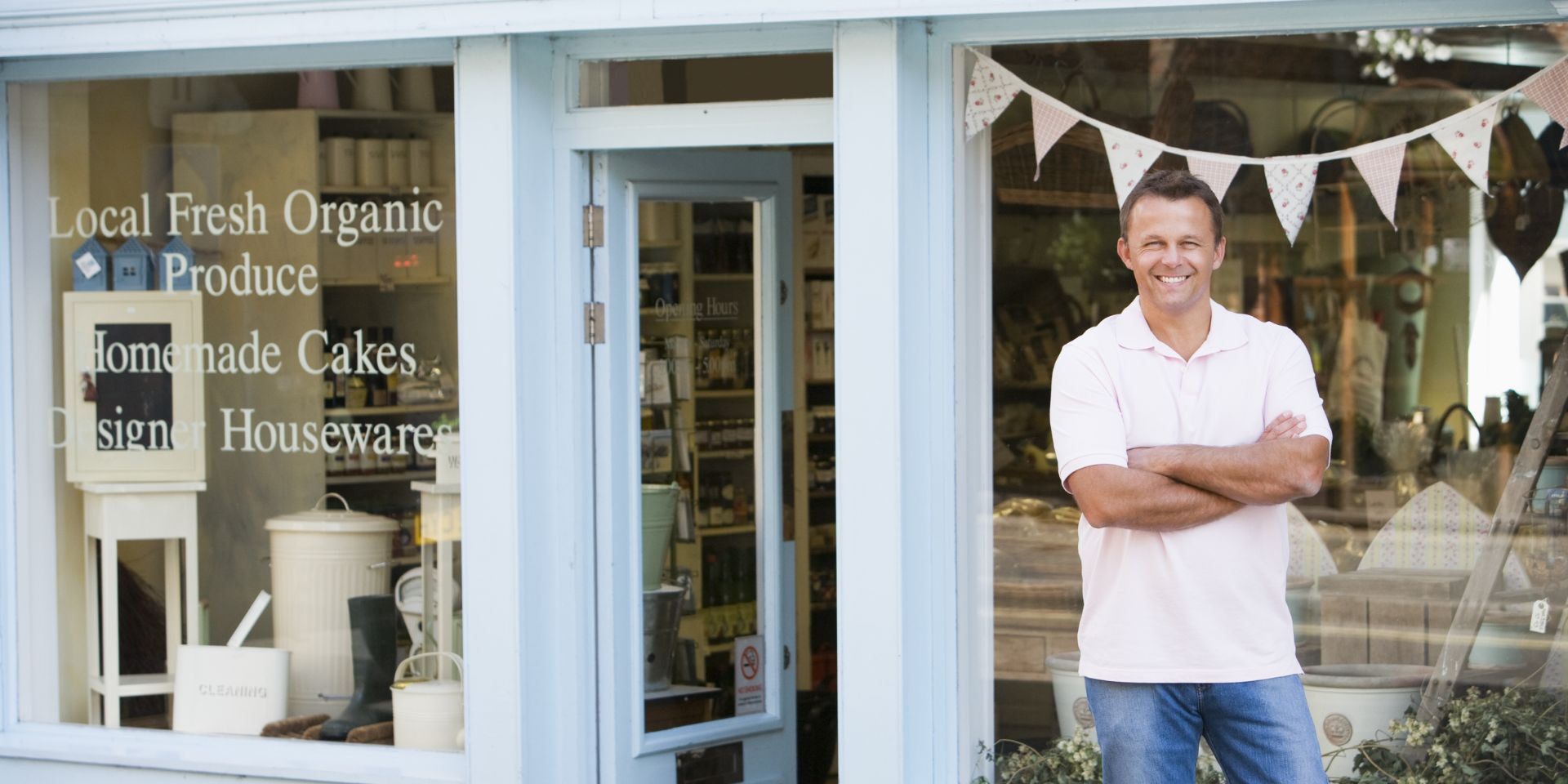 A male shop owner stands outside of his shop display.