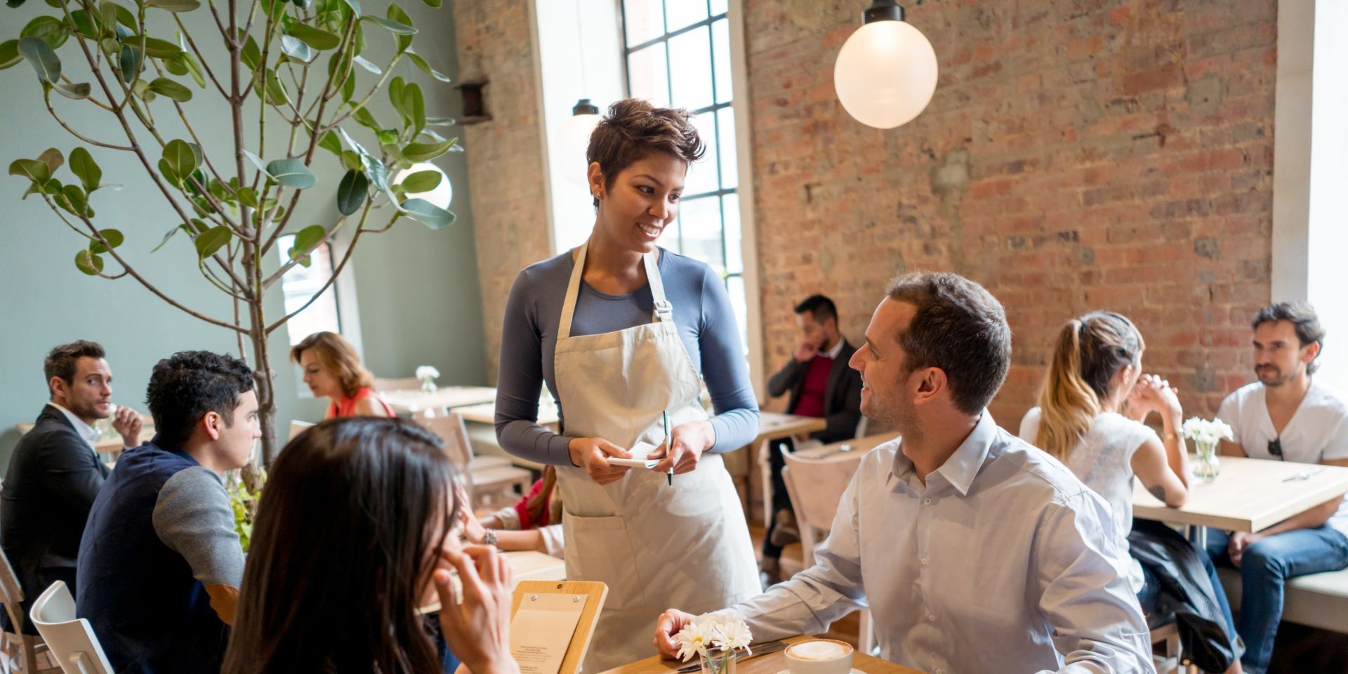 A waitress serves a coupe sat inside a restaurant.