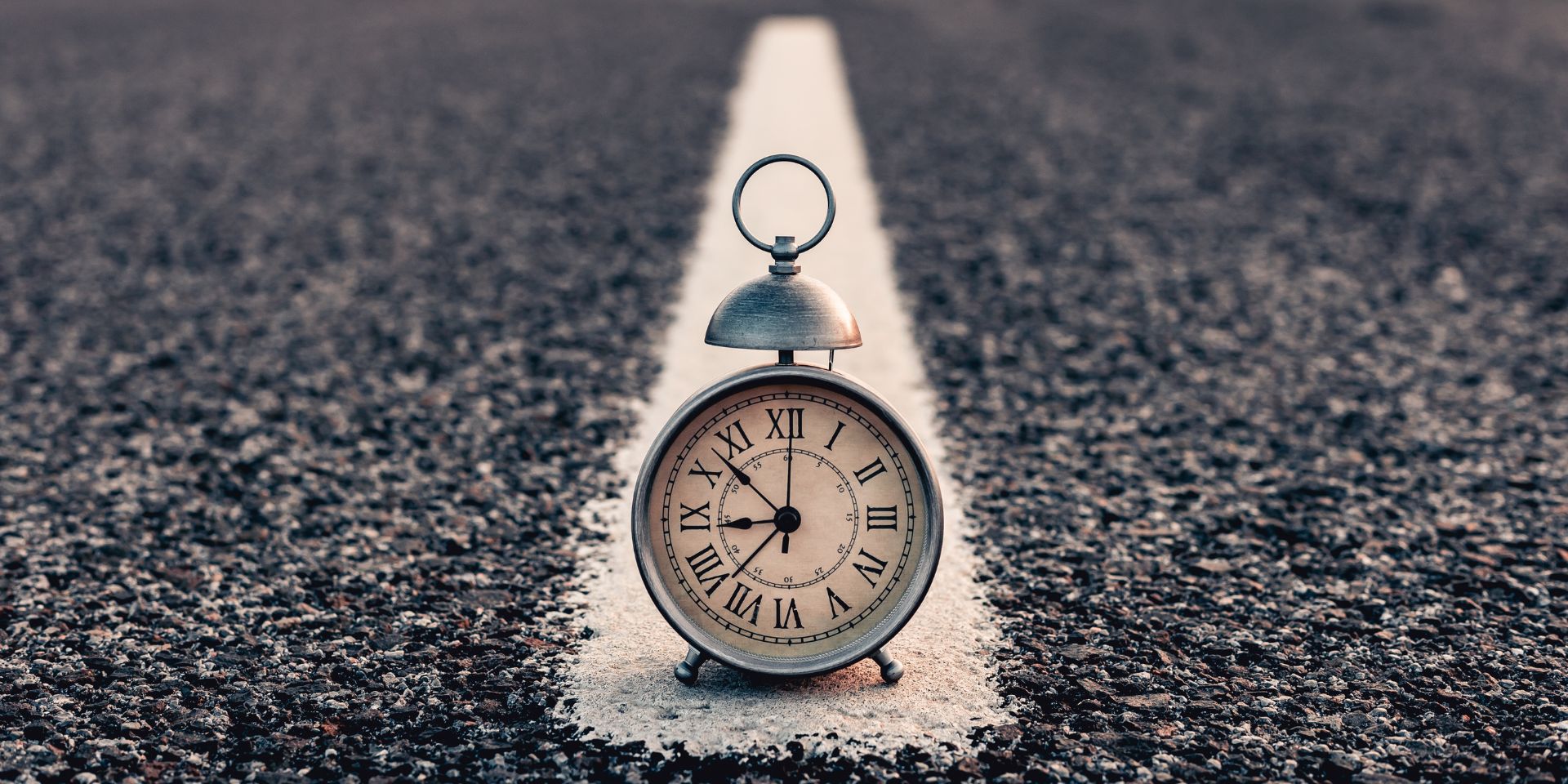 An old fashioned alarm clock on a road.