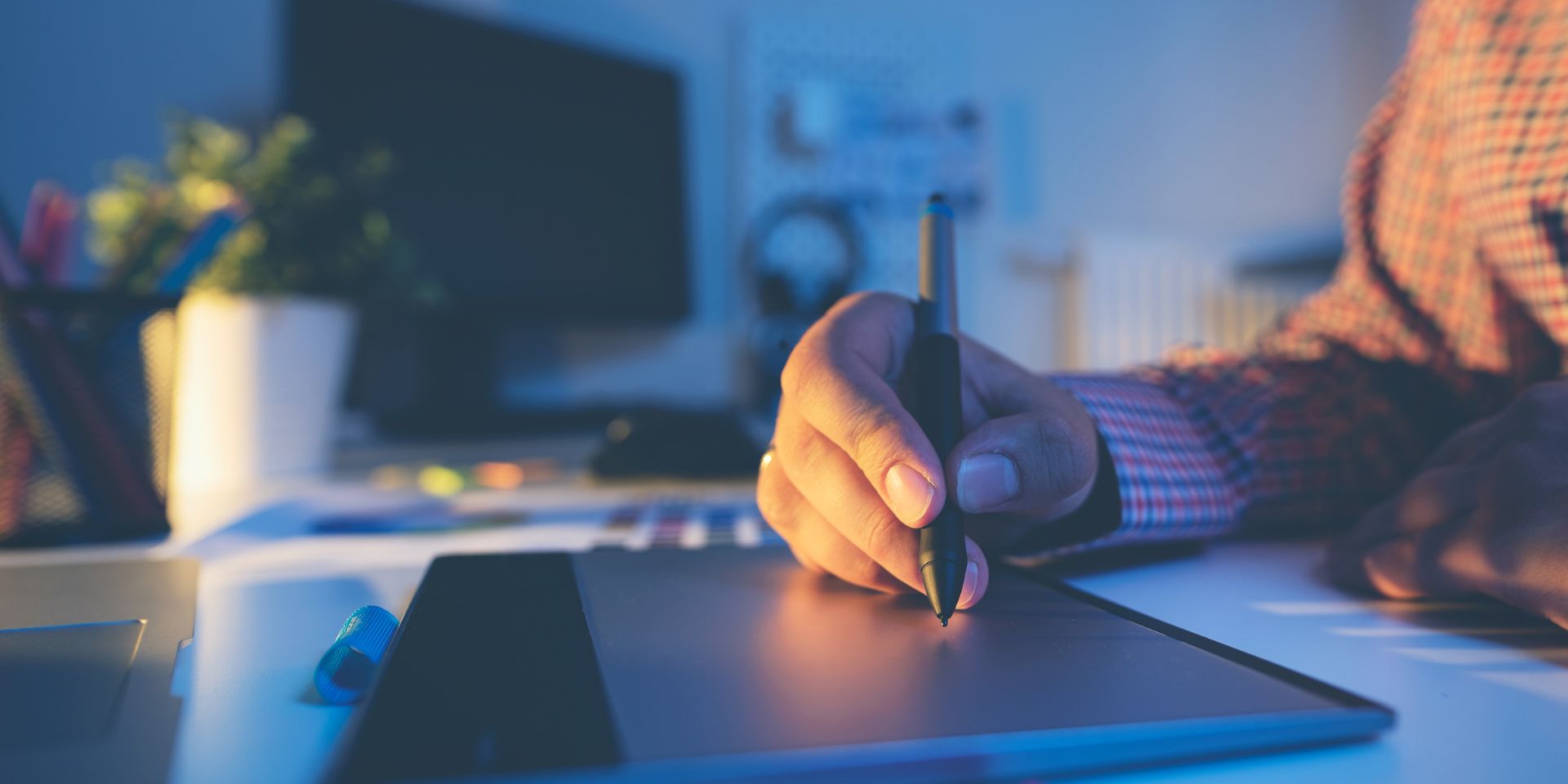 A graphic designer works in their office, with a close-up view of their hands.